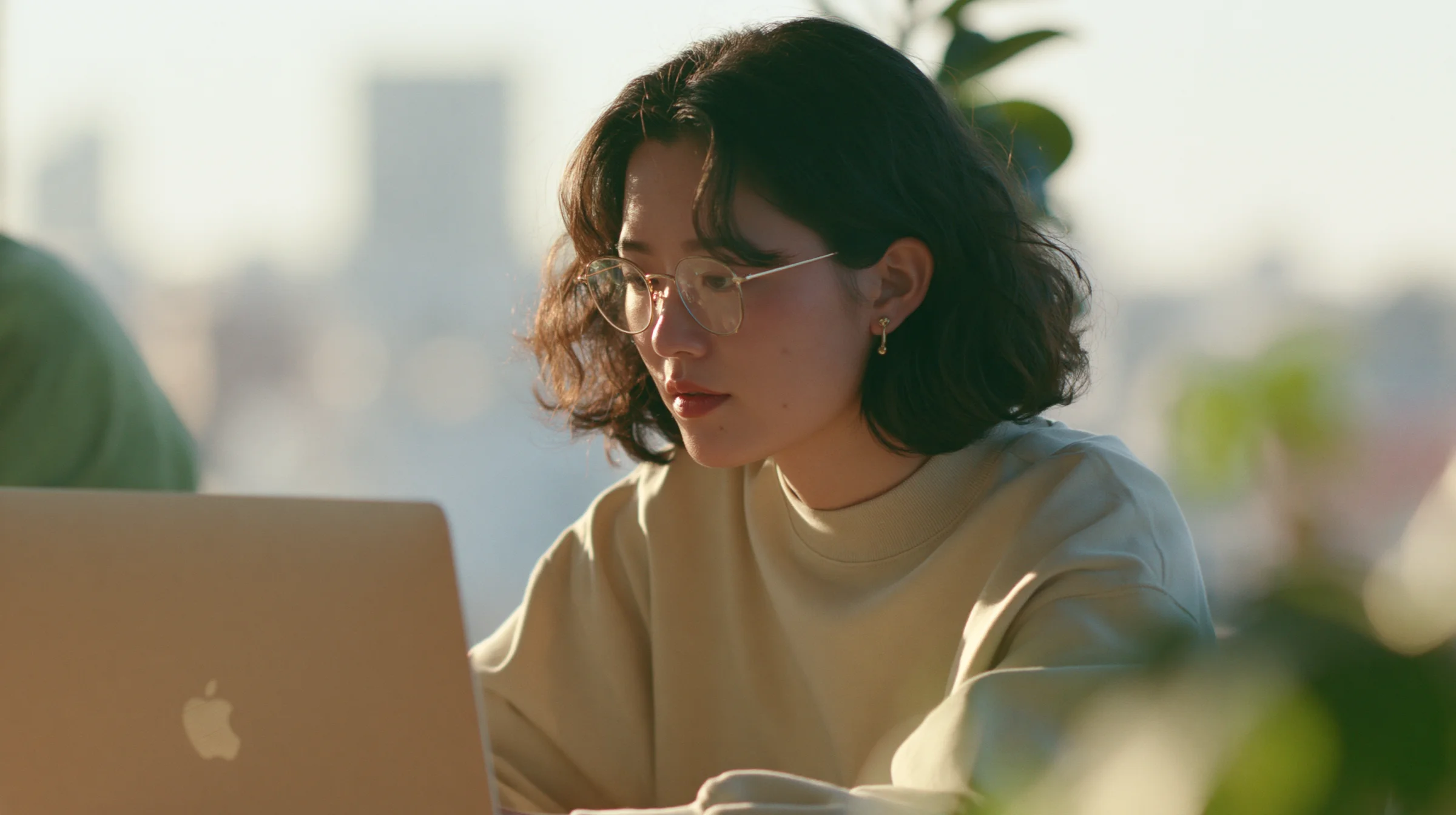 A campaign manager writing creator outreach on a laptop in warm sunlight